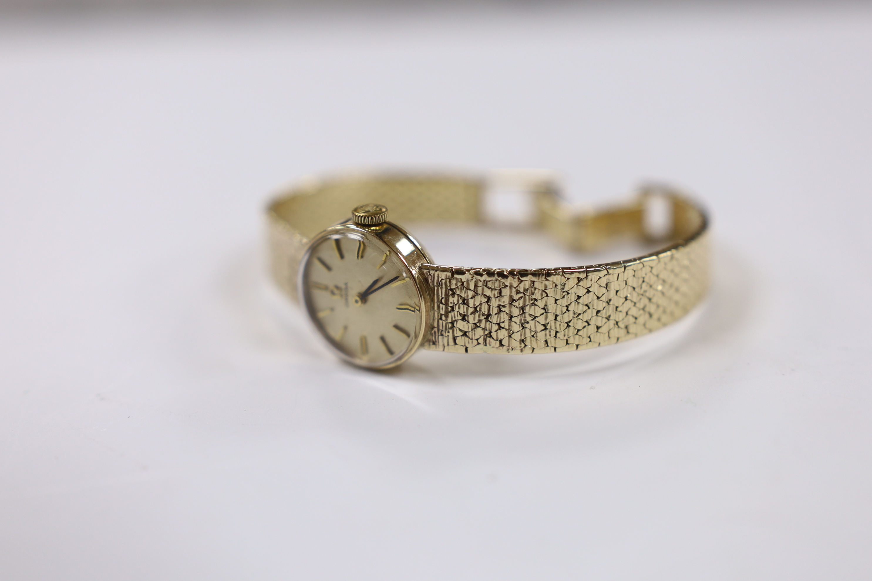 A lady's 9ct gold Omega manual wind wrist watch, on integral 9ct gold bracelet, overall length 15.5cm, gross weight 21.9 grams.